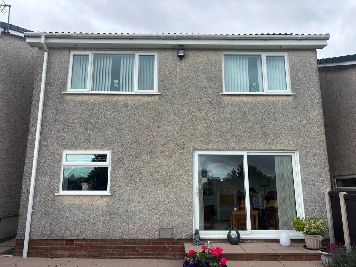 Rear of a detached house with grey, stained render before soft washing