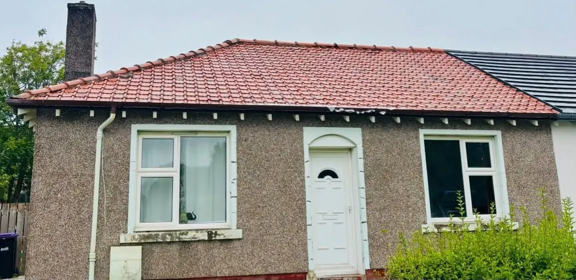 The same bungalow roof after moss removal and treatment, bright red tiles restored